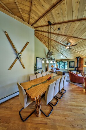 A spacious dining area with a long wooden table and cushioned chairs, a wooden ceiling with exposed beams, and a hanging light fixture. - COZY, sunny, 5 big bedrooms, 3 baths, 3500 sq ft, Trees, 4 miles to Winter Park (Fraser)