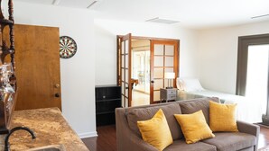 Ein modernes Wohnzimmer mit einer Couch, einem Dartboard und einer Holztür.