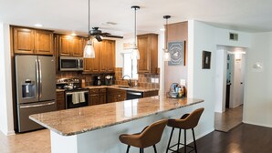 Eine moderne Küche mit Granit-Arbeitsplatten, Edelstahlgeräten und Holzschränken.