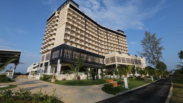 A large hotel with multiple floors and balconies, surrounded by well-maintained gardens and palm trees. - Amerald Resort Hotel Desaru (Bandar Penawar)