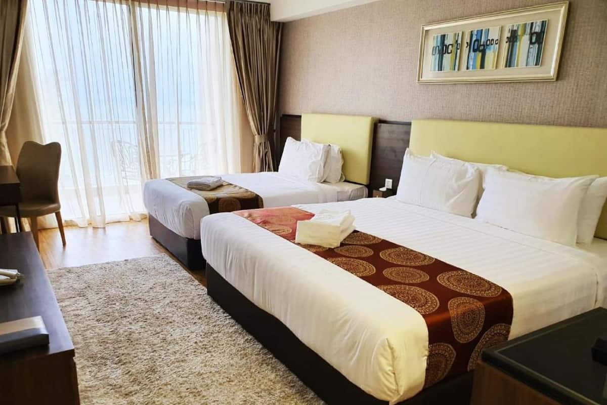 A hotel room with two beds, a desk, a chair, and a large window with curtains.