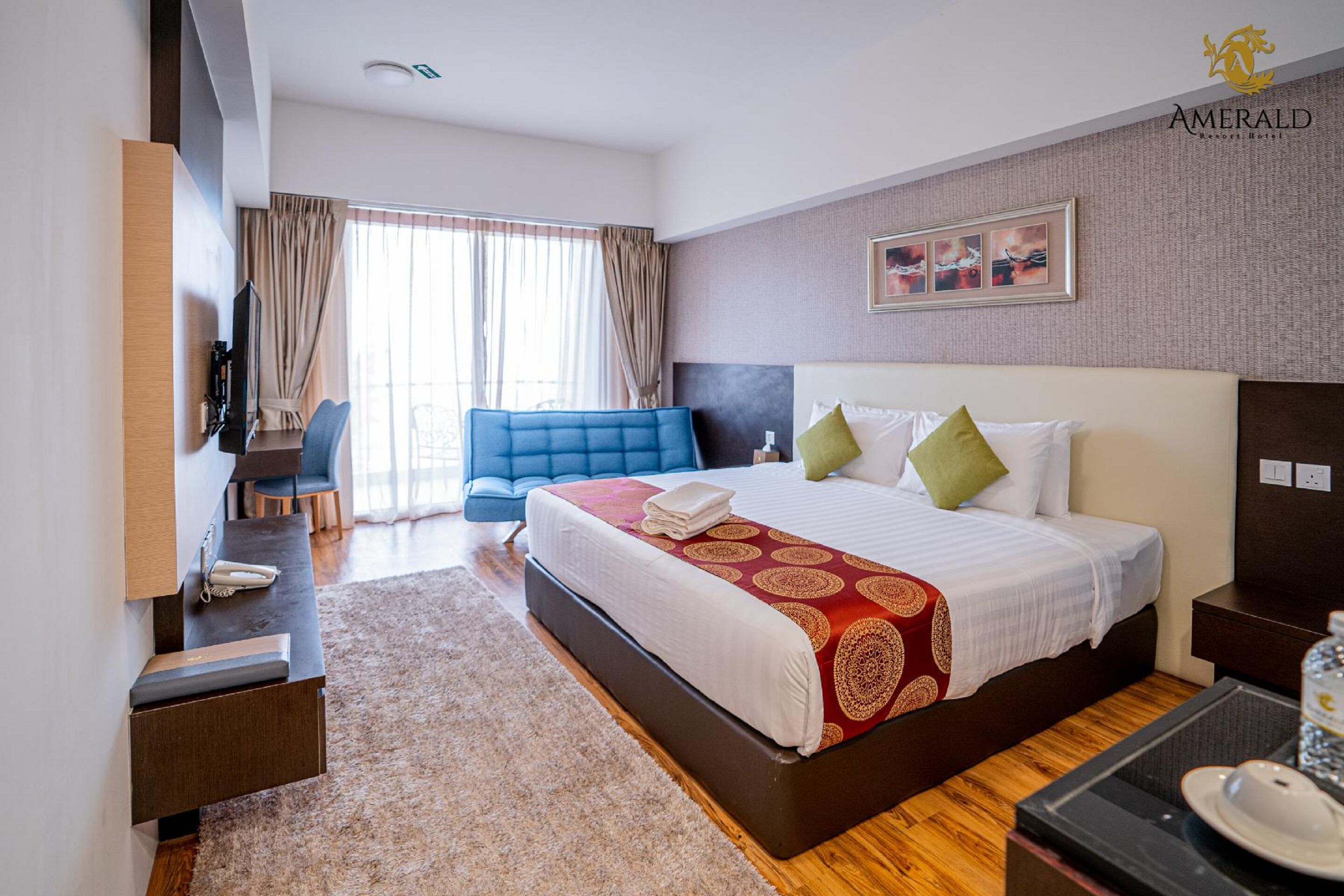 Habitación de hotel con una cama grande, un escritorio, una silla, un televisor y vistas al exterior.