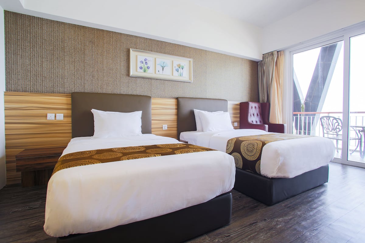 A hotel room with two beds, a large window, and a balcony.