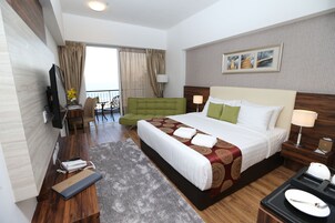 Habitación de hotel con una cama grande, un escritorio con computadora, una silla y un televisor.