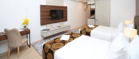 Habitación de hotel con dos camas, un escritorio, un televisor y un espejo.