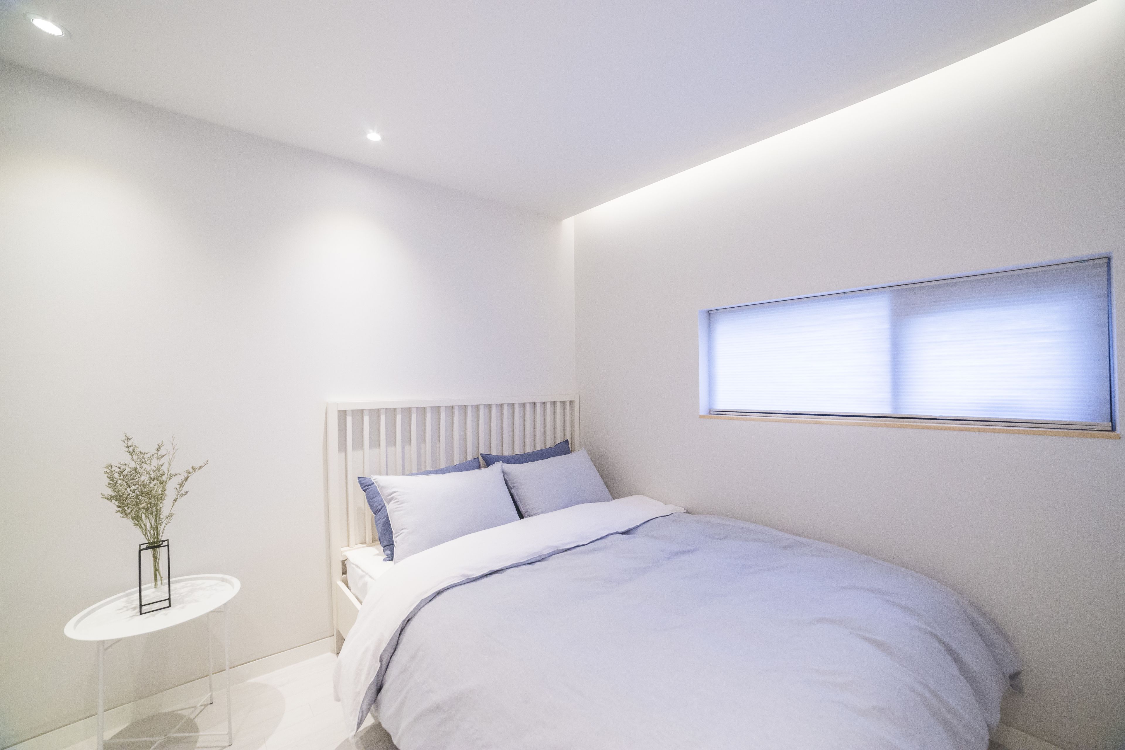 Un dormitorio moderno con cama, mesita de noche y ventana.