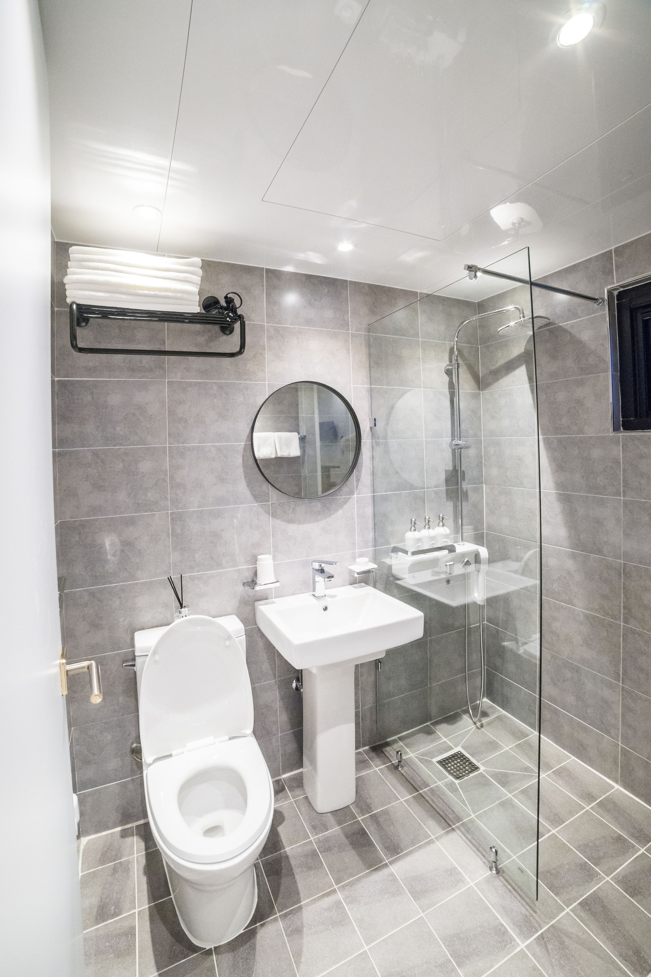Un baño moderno con inodoro, lavamanos y cabina de ducha con mampara de vidrio.