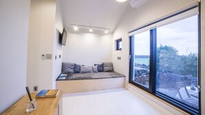 Une chambre à coucher moderne avec un banc intégré, une grande fenêtre et une vue sur l’extérieur.