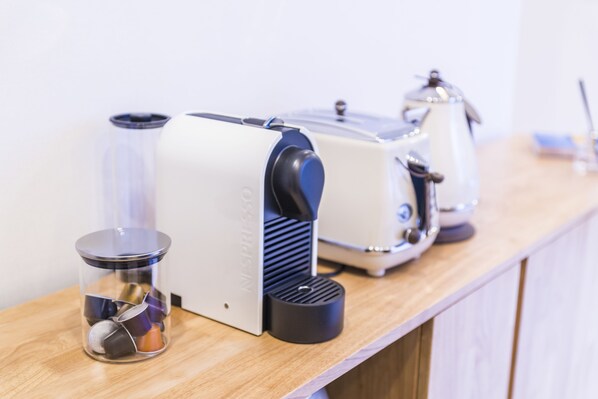 A coffee machine, a kettle, and a coffee grinder on a wooden countertop.