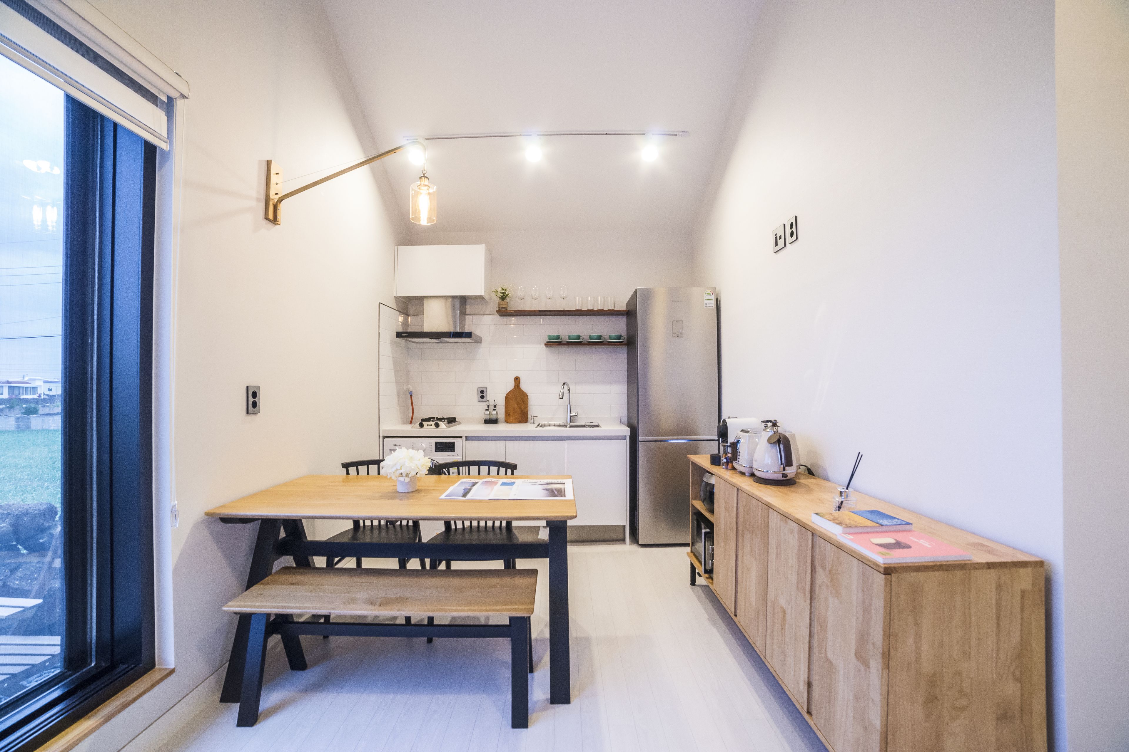 A compact kitchen with a dining area, a wooden bench, and a built-in wooden cabinet.