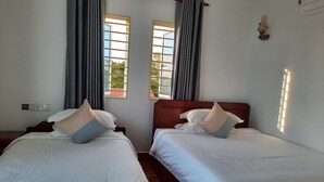 Two single beds with white linens and pillows, a wooden headboard, a window with a view, and a wall-mounted light fixture. - Realkhom Homestay (Siem Reap)