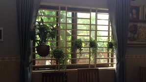 A dining area with a window, a hanging plant, and a table. - Realkhom Homestay (Siem Reap)