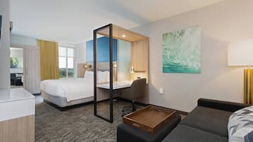 Habitación de hotel con cama, escritorio, silla y una pequeña mesa de madera.
