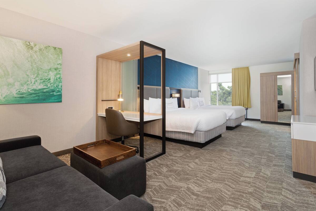 A hotel room with a bed, a desk, a chair, and a sofa.
