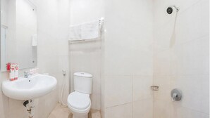 Une salle de bain avec un lavabo, des toilettes et une douche, le tout de couleur blanche.