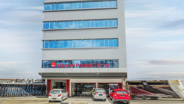 Un hôtel à plusieurs étages, doté d’une façade moderne, d’une entrée bien visible et de plusieurs voitures garées devant.