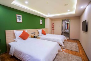 Een hotelkamer met twee bedden, groene wanden, een plafondlamp, een spiegel en een televisie.