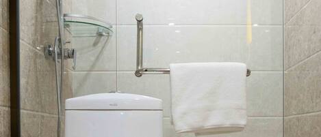 A modern bathroom with a glass-enclosed shower, a white toilet, and a glass shelf with toiletries.