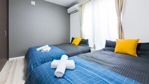 A hotel room with two beds, grey walls, and a window with curtains. - Mikazuki House Teradacho (Osaka)