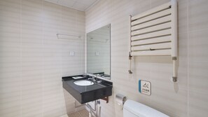 Une salle de bain équipée d’un lavabo, d’un miroir, d’un porte-serviettes et de toilettes.