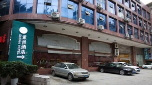 A hotel with a modern facade, multiple air conditioning units, and a parking area with several cars. - Sucha Hotel Chongqing Jiefangbei (Chongqing)