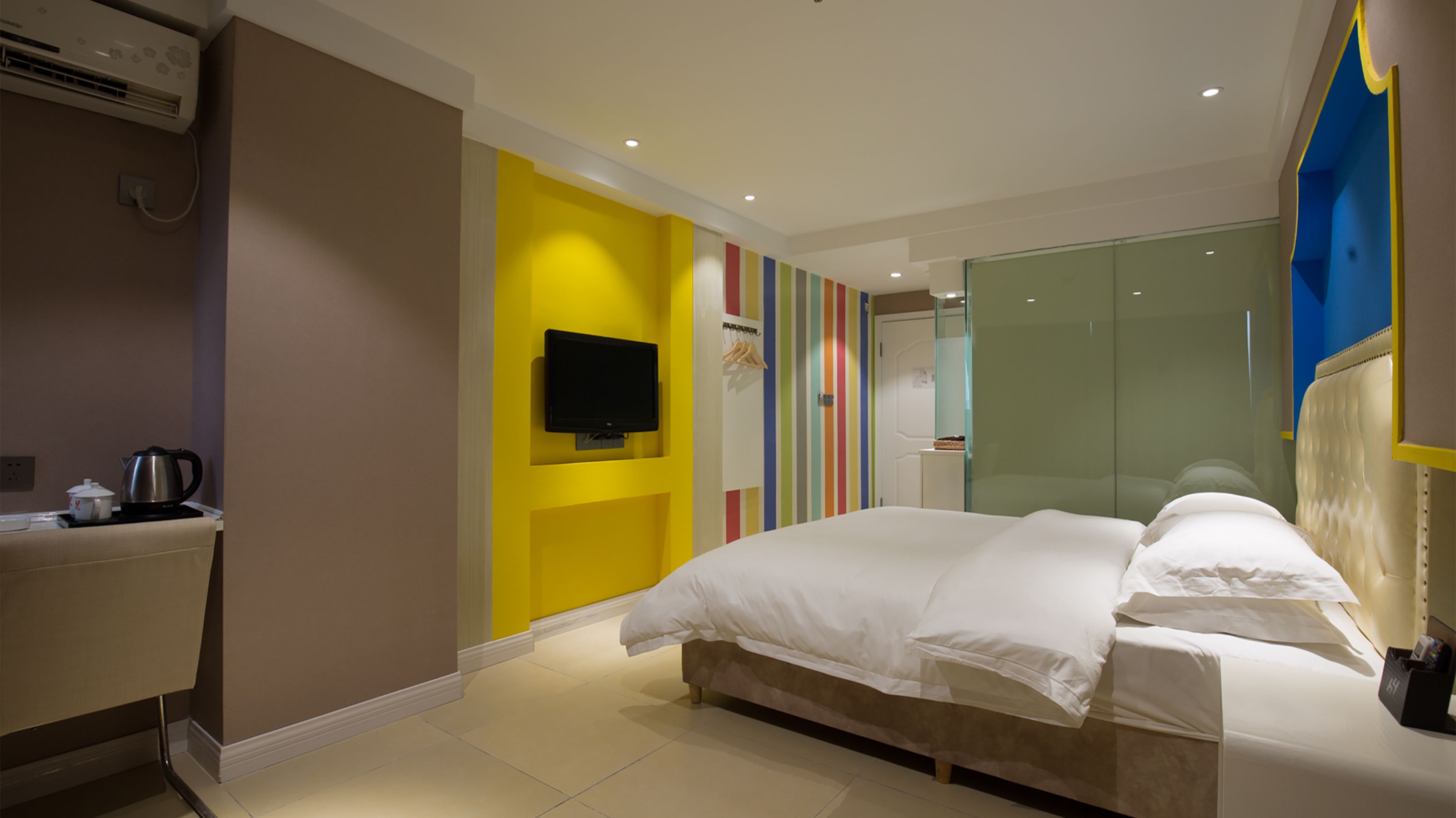 Une chambre d’hôtel moderne équipée d’un lit, d’une télévision, d’une machine à café et d’une douche en verre.