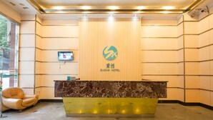 A hotel reception area with a marble counter, a leather chair, and a digital screen on the wall. - Sucha Hotel Chongqing Jiefangbei (Chongqing)