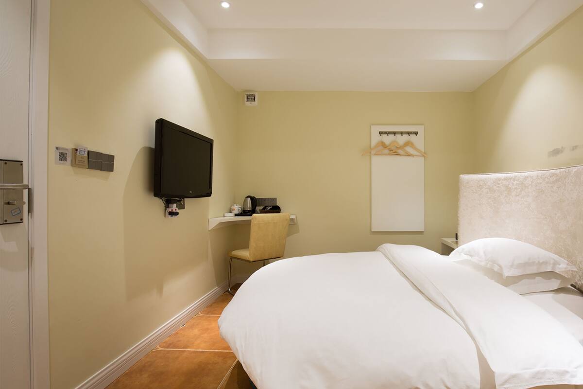 A hotel room with a bed, a TV, a desk, and a mirror.