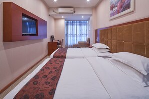 Una habitación de hotel con dos camas, un televisor montado en la pared, un escritorio y una silla.