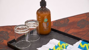 A bottle of body hair remover, two empty glasses, and a tray with a tissue on a table with a floral pattern. - Sucha Hotel Chongqing N. Railway Station (Chongqing)