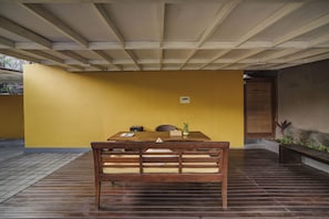 A wooden dining table with chairs, a yellow wall, and a ceiling with wooden beams. - La Mira Villa Seminyak by Ini Vie Hospitality (Kerobokan)