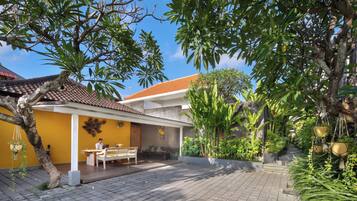 A courtyard with a tiled floor, a wooden bench, a table, and a hanging plant.