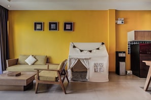 A modern living room with a yellow wall, a sofa, a small table, a wooden chair, and a tent-like structure. - La Mira Villa Seminyak by Ini Vie Hospitality (Kerobokan)