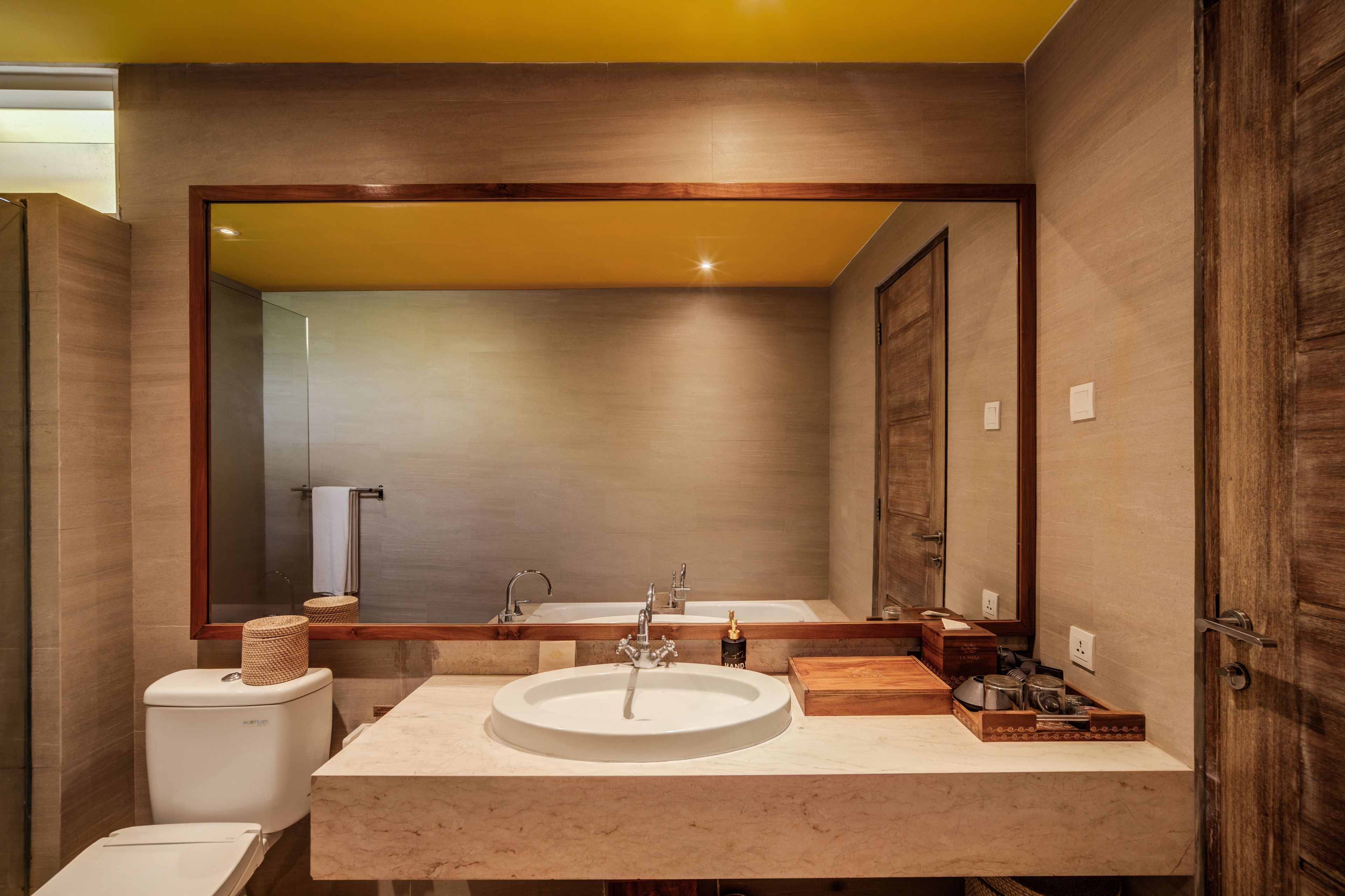 A modern bathroom with a large mirror, a sink, and a toilet.