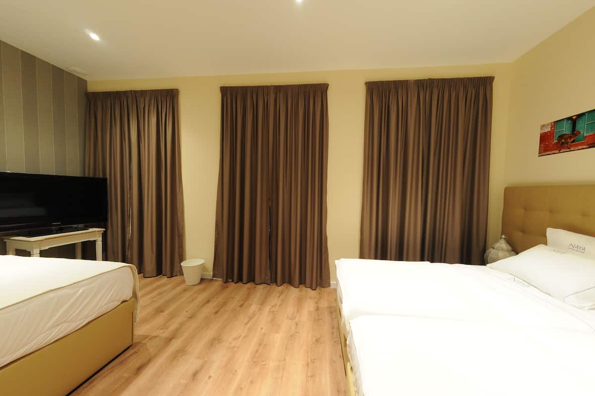 Habitació d'hotel amb dos llits, televisió, taulell de nit i cortines.