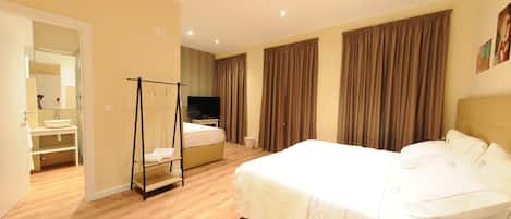 A hotel room with a large bed, a bedside table, a TV, and a bathroom with a sink and mirror.