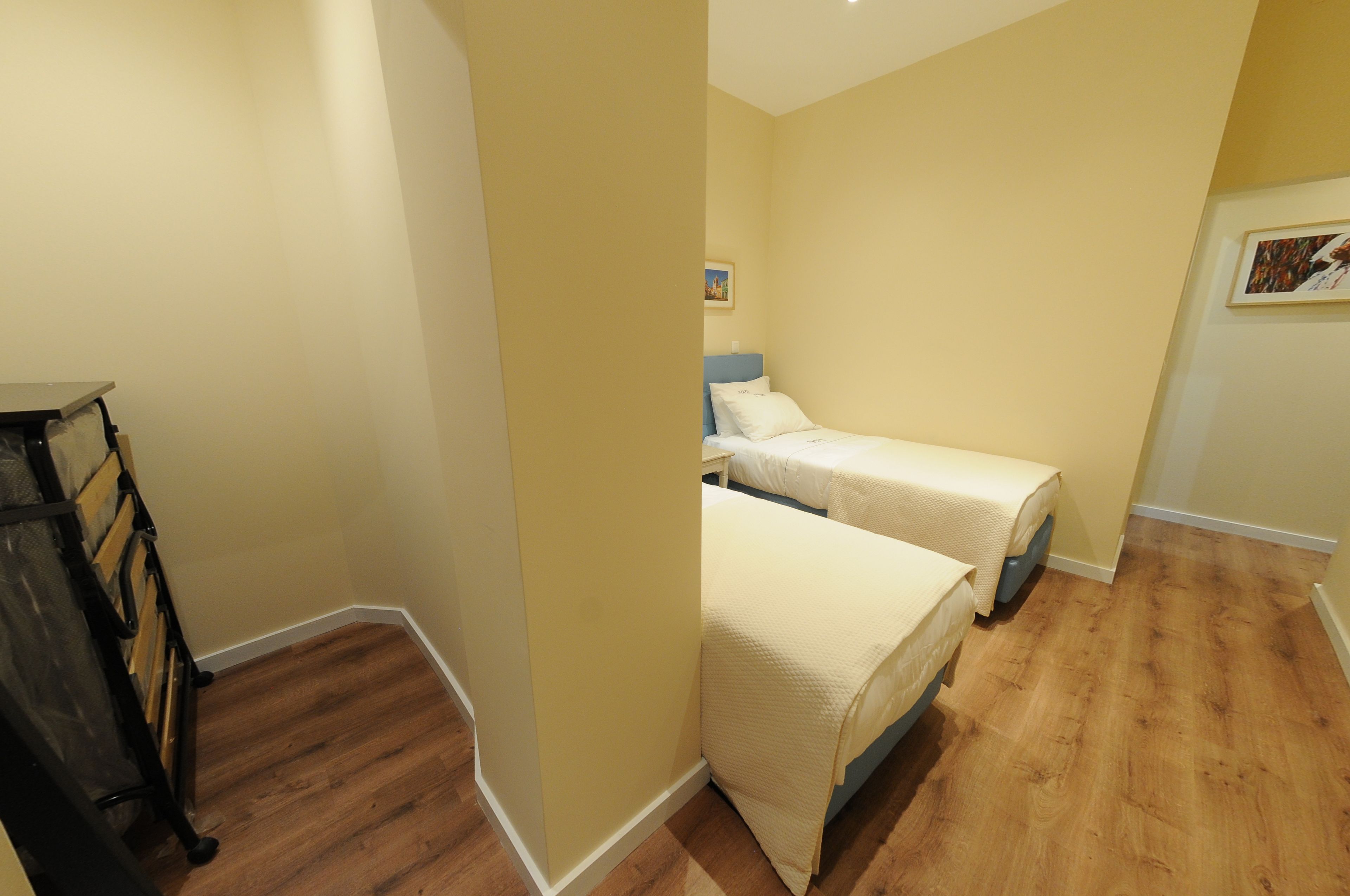 A bedroom with two single beds, wooden flooring, and a small desk.