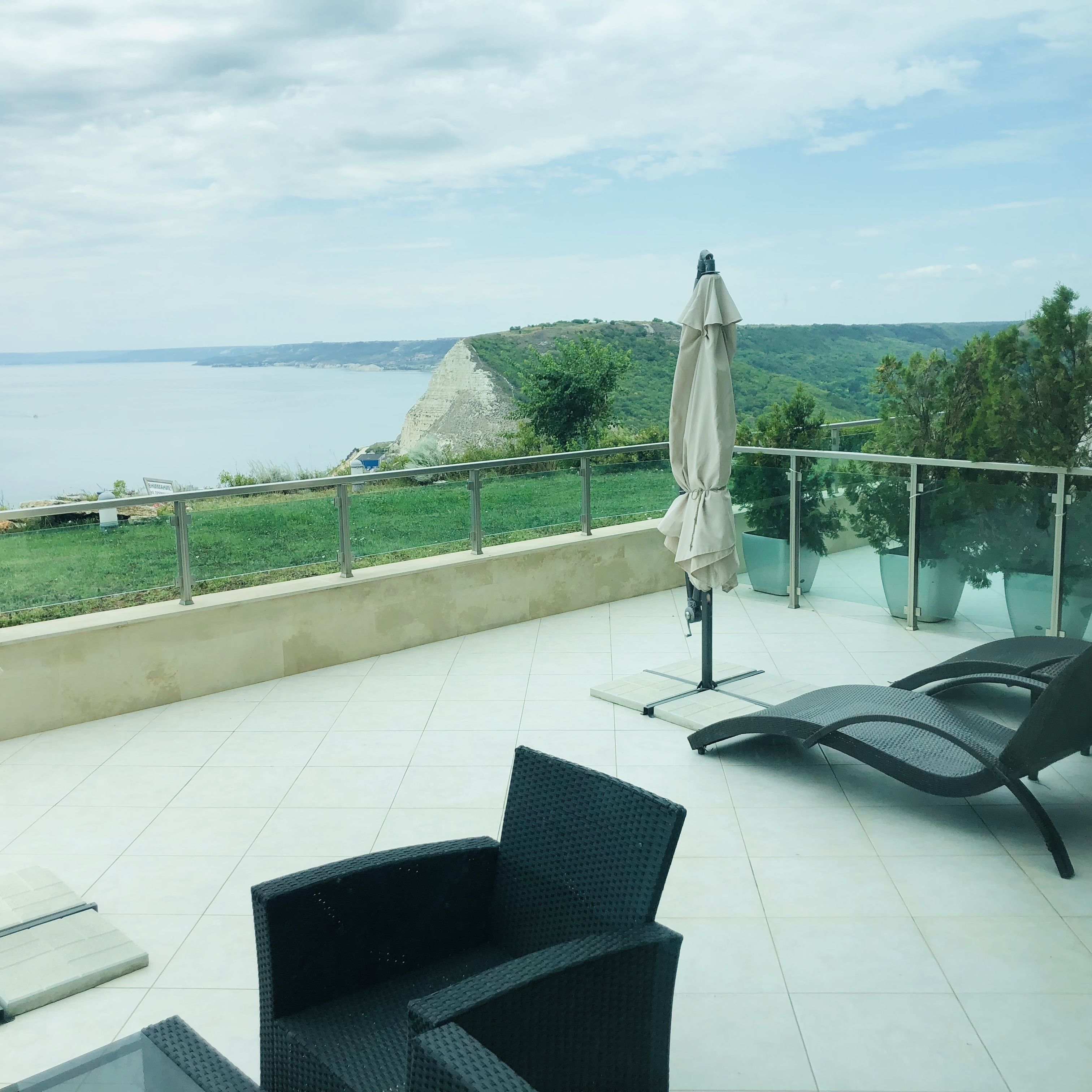 Une terrasse avec vue sur la mer, une table, des chaises et un parasol.