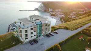 Un bâtiment moderne doté d’une façade en verre, d’un espace de stationnement et offrant une vue sur la mer.