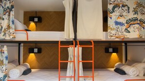 Quarto com beliches, duas camas, cada uma com cabeceira, escada e luminária fixada na parede.