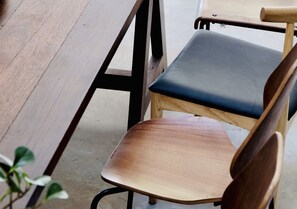 A wooden chair with a dark cushion and a metal frame. - TAN Hostel x Cafe - Adults Only (Krabi)