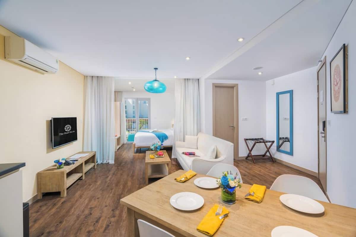 A hotel room with a dining area, a TV, a bed, and a view of the outdoors.