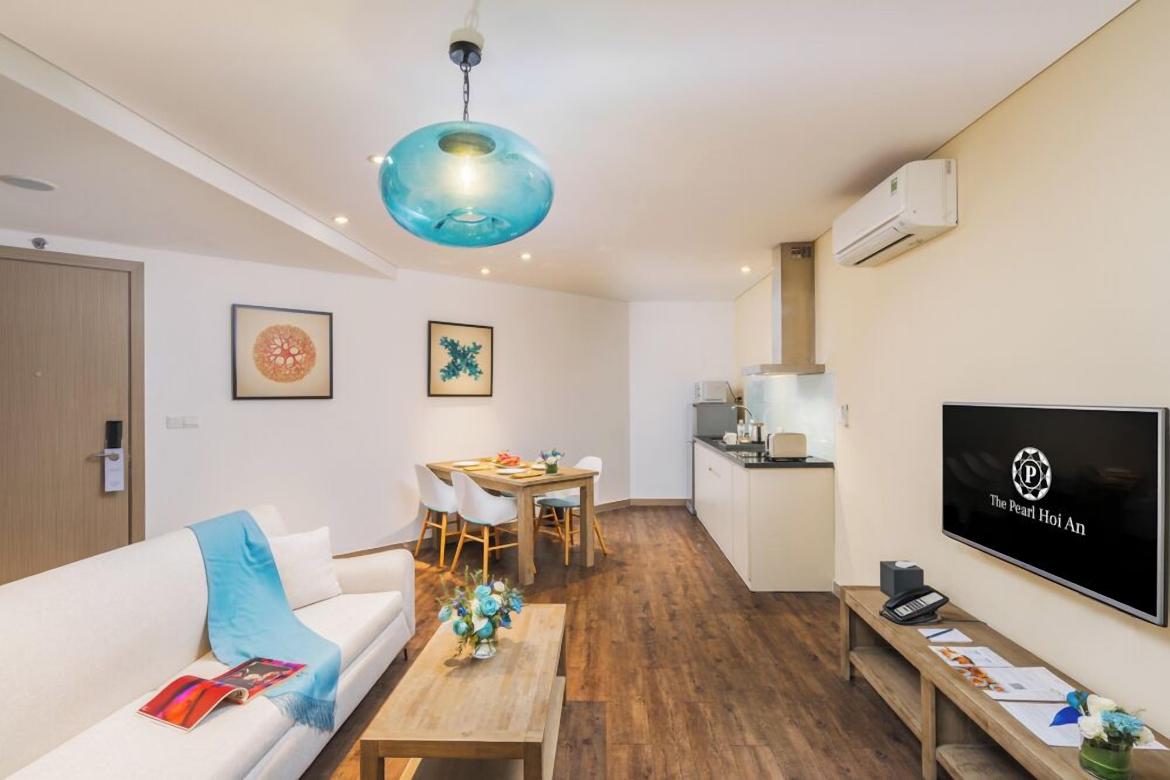 En moderne stue med sofa, sofabord, spiseområde og køkken.