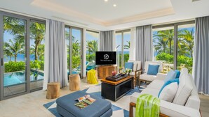 A modern living room with a large TV, comfortable seating, and a view of the ocean. - The Pearl Hội An (Da Nang)