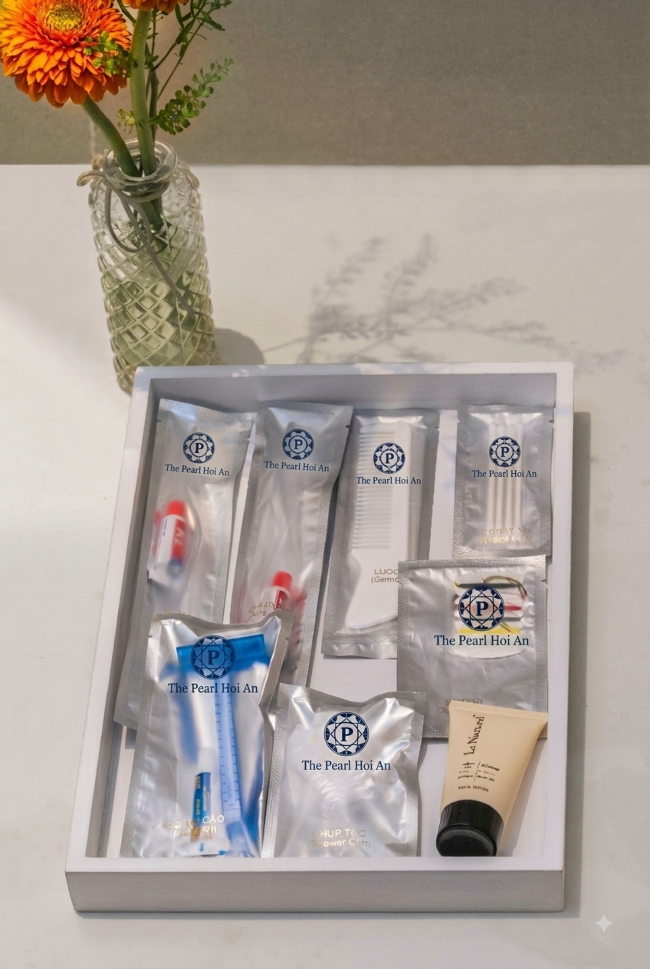 A white box containing various skincare products from The Pearl Hoi An, including tubes, bottles, and sachets.
