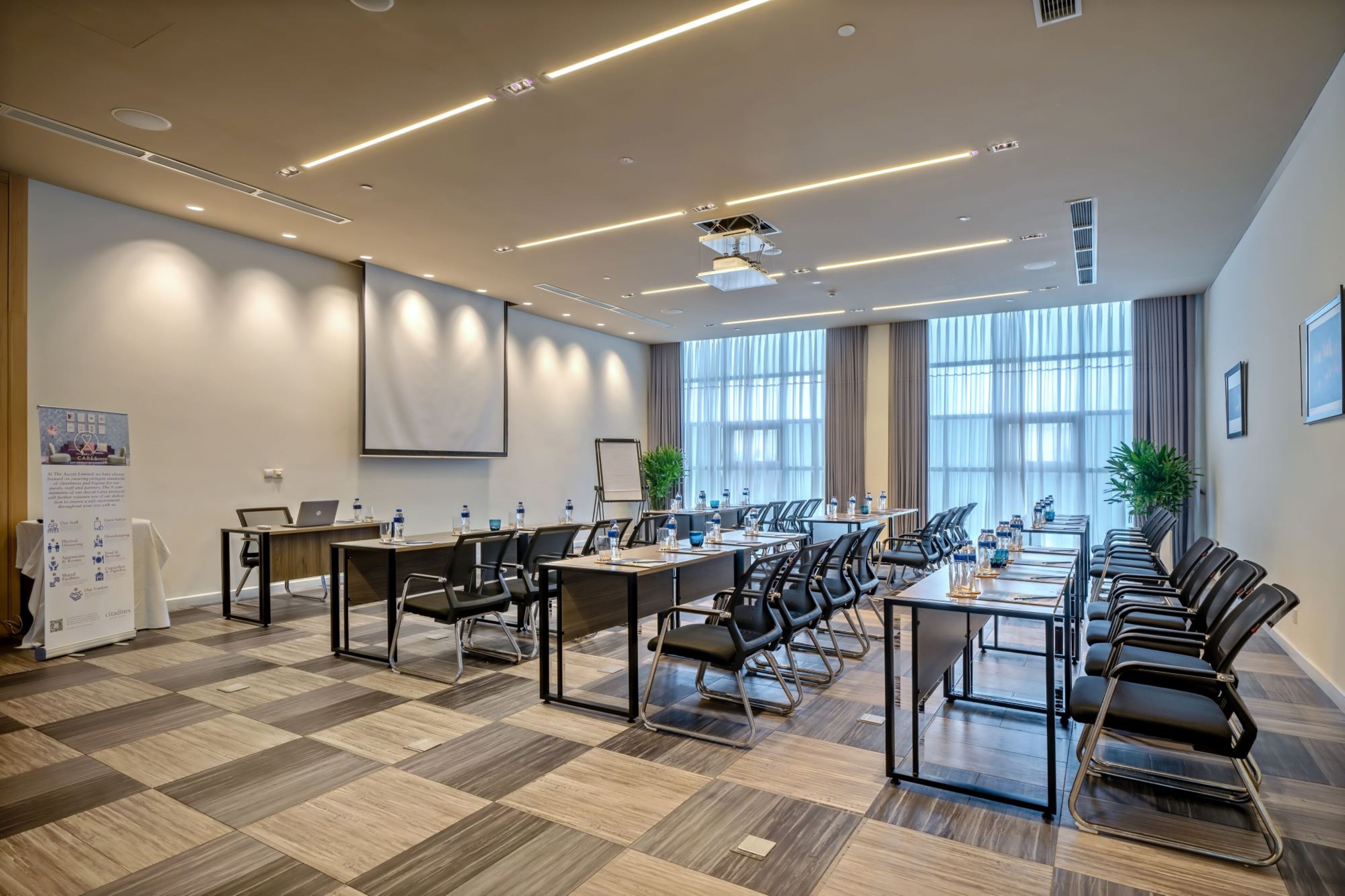 A conference room with a long table, chairs, and a projector screen.