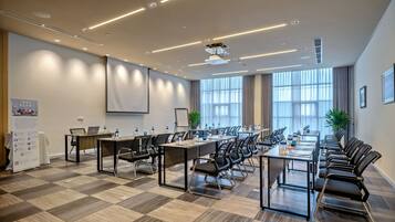 A conference room with a long table, chairs, and a projector screen.