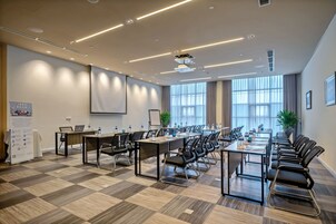 A conference room with a long table, chairs, and a projector screen.