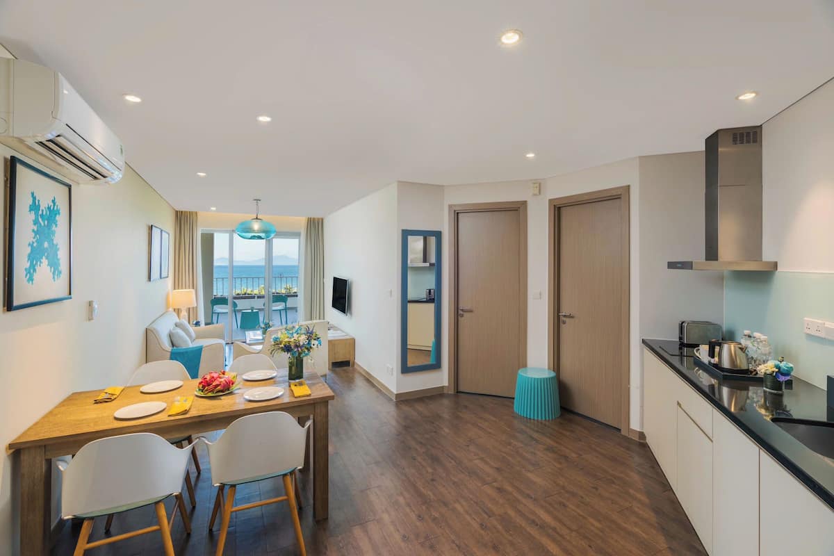 A modern kitchen with a dining area, a view through the window, and a large mirror.