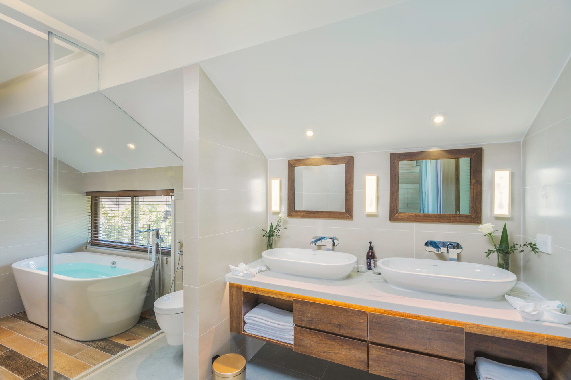A modern bathroom with a large bathtub, two sinks, and a glass shower enclosure.